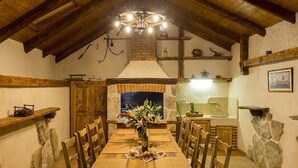 Une salle à manger rustique avec une table en bois, des chaises et un lustre.
