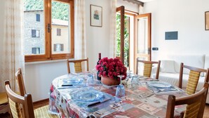 A dining area with a table set for four, a potted plant, and a view of a building outside.