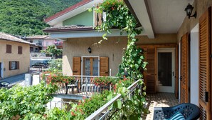 A balcony with a table and chairs, a door, and a view of a mountain.