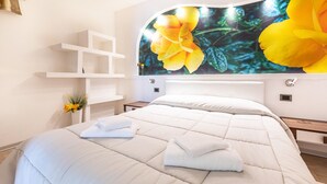 A hotel room with a bed, a white wall, a shelf unit, and a large floral mural. - In hilly surroundings with spectacular views – Apartment GeoResort B8 (Tremosine)