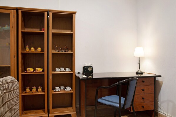 A room with a wooden cabinet, a desk, a chair, and a lamp.