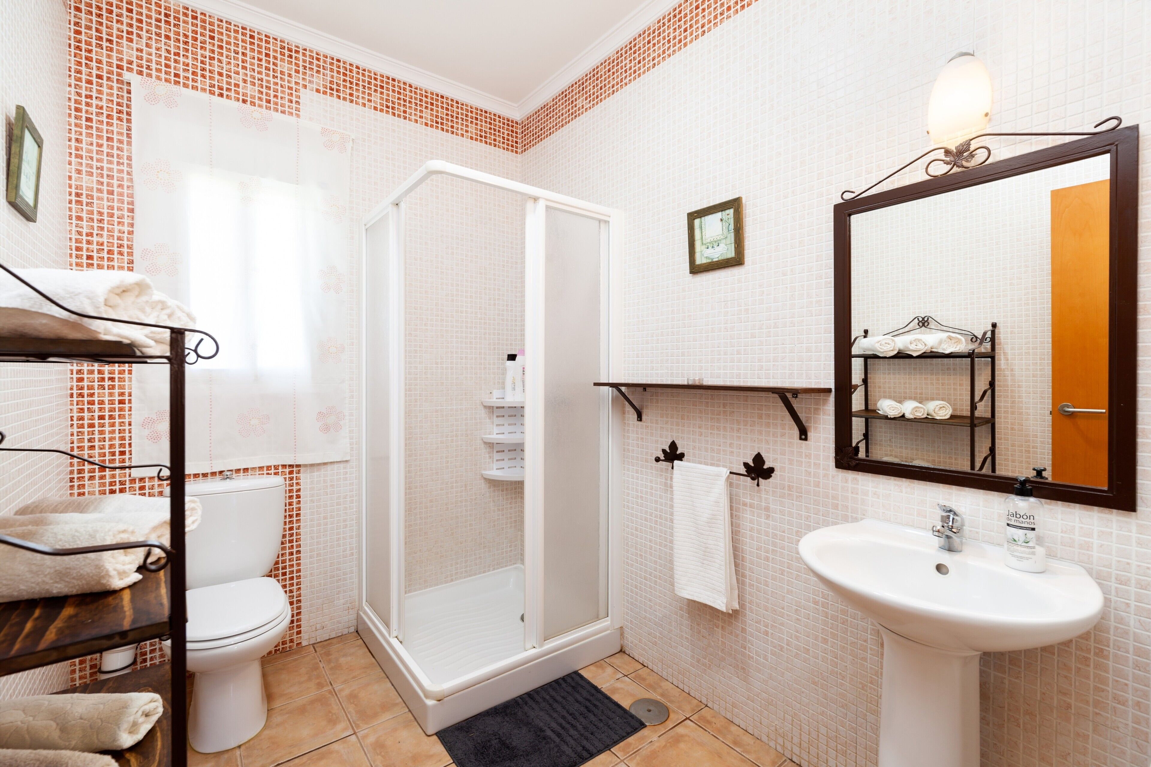 Ein Badezimmer mit Toilette, einer Dusche mit Glaswand, einem Waschbecken mit Spiegel und einem Handtuchhalter.