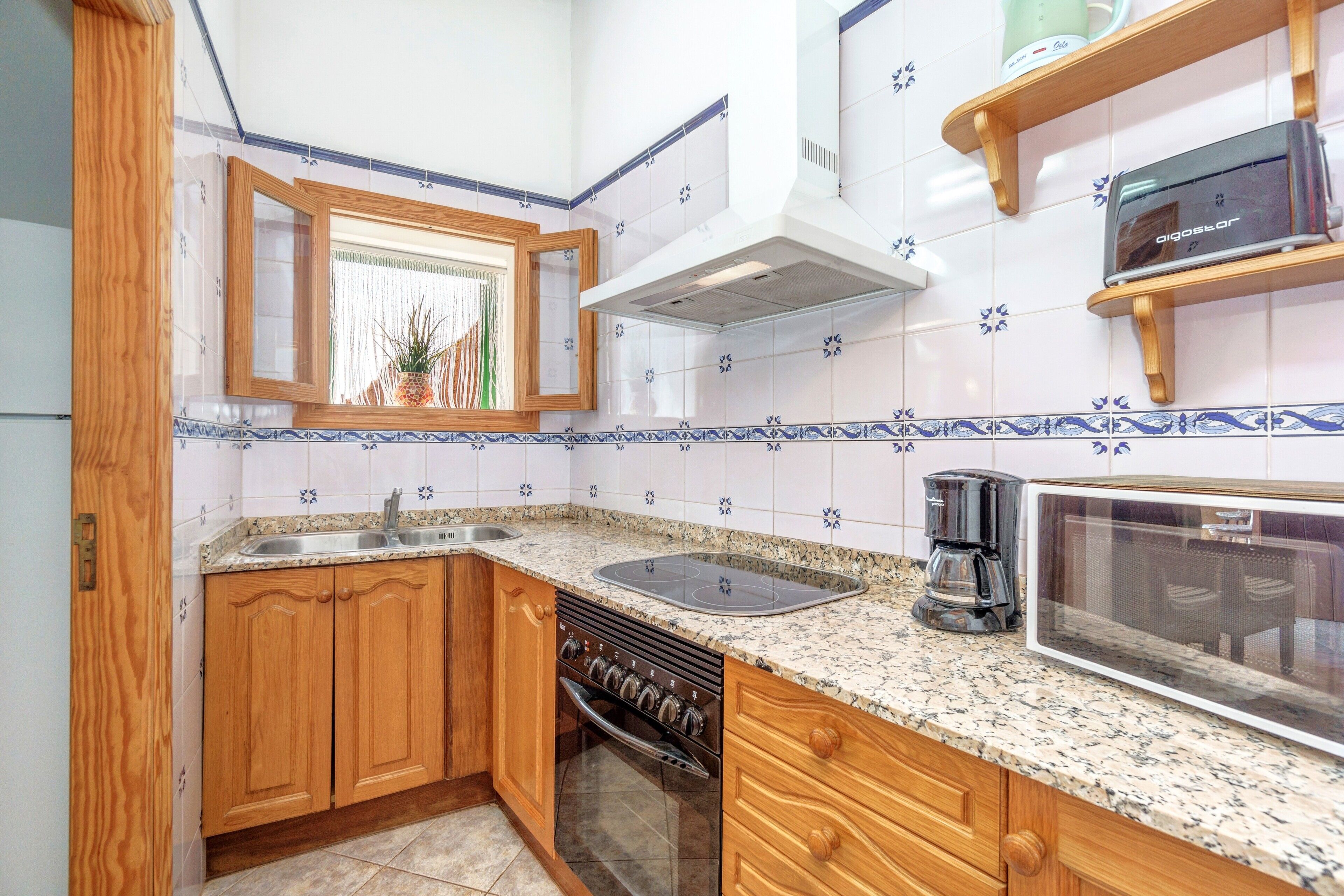 A kitchen with wooden cabinets, a built-in oven, a microwave, and a coffee maker.