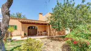 A rustic house with a tiled roof, a wooden door, and a small patio with outdoor seating. - Country house "Sa Barraca d'en Camine" with pool in the nature (portopetro)