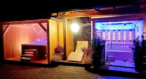 A spa area with a hot tub, wooden seating, and a stone wall.