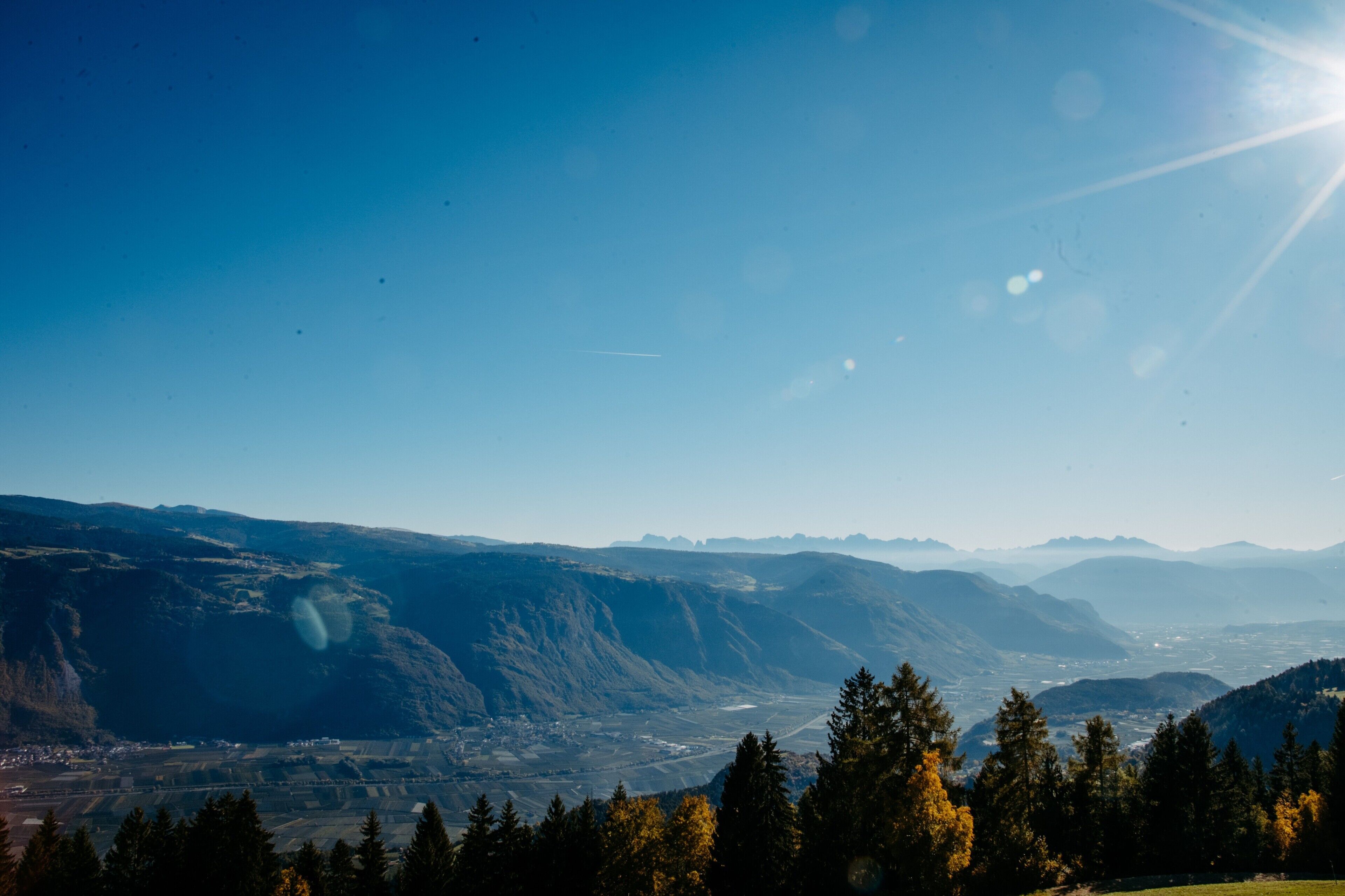 Paesaggio montuoso con cielo sereno e paese in lontananza.