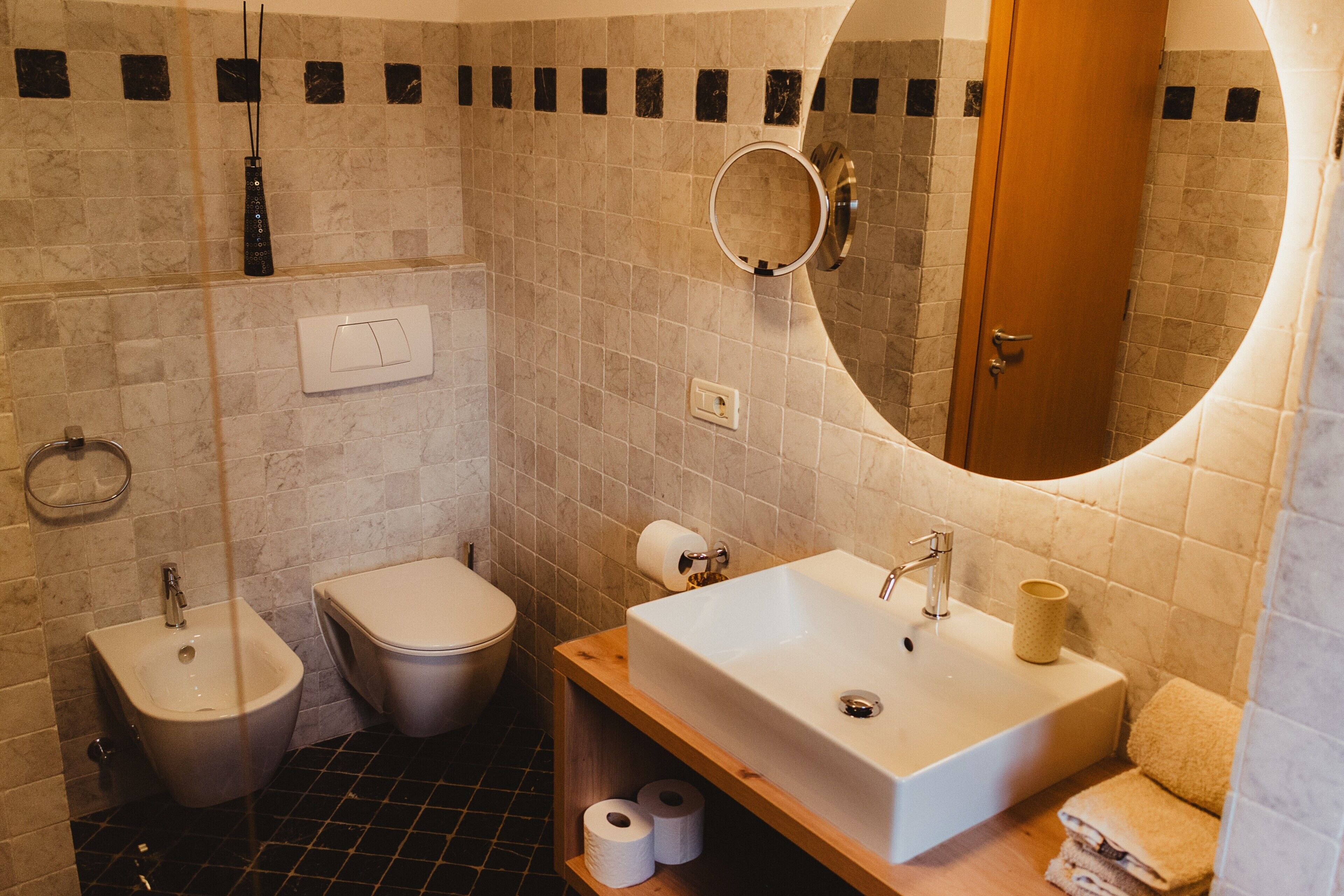 Un bagno con bidet, water, lavandino, specchio e porta asciugamani.