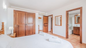A hotel room with a large bed, wooden wardrobe, a mirror, and a bathroom visible through an open door. - Peaceful location with pool - Villa Can Jaume (Pollença)