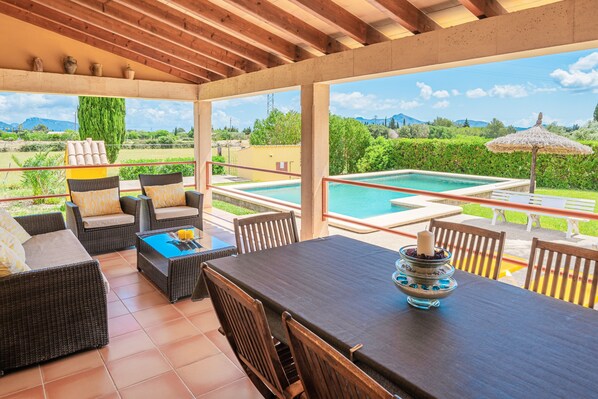 An outdoor patio with wicker furniture, a dining table, and a pool.