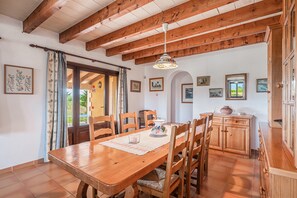 A dining area with a wooden table, chairs, and a hanging light fixture.