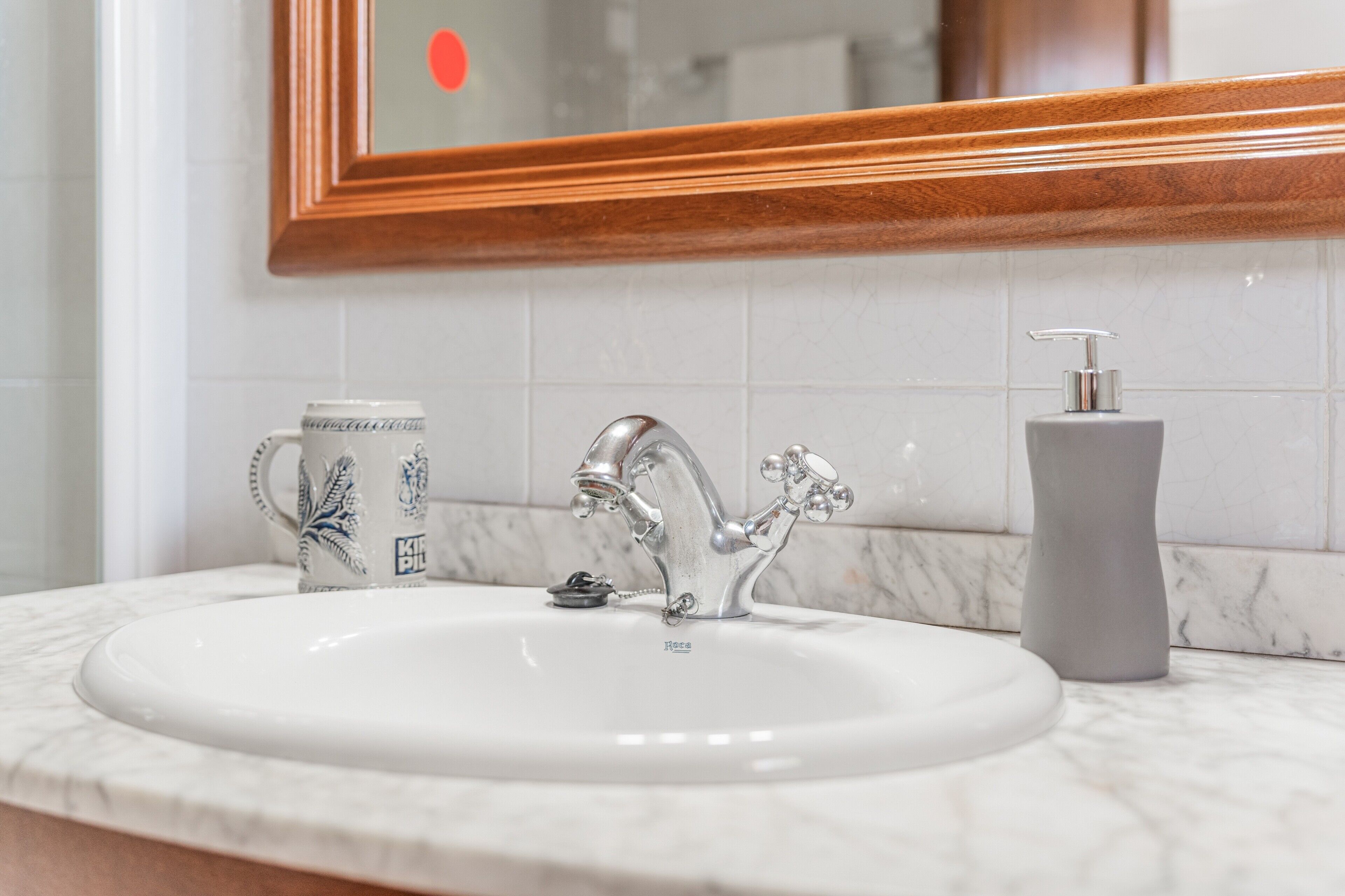 A bathroom sink with a modern faucet, a soap dispenser, and a decorative mug.