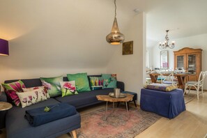 Un salon comprenant un canapé, un pouf, une table basse et un lustre.
