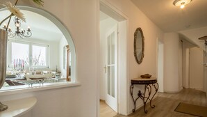 Um corredor com espelho, um candelabro, uma mesa com uma tigela e um tapete.