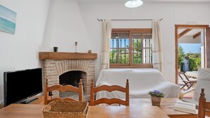 Una stanza con camino, televisione, tavolo da pranzo e vista sull'esterno.
