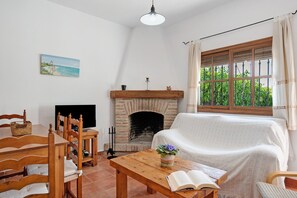 A living room with a fireplace, a sofa, a dining table with chairs, and a painting on the wall.