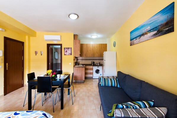 A compact living space with a dining area, kitchenette, and a sofa with striped cushions.