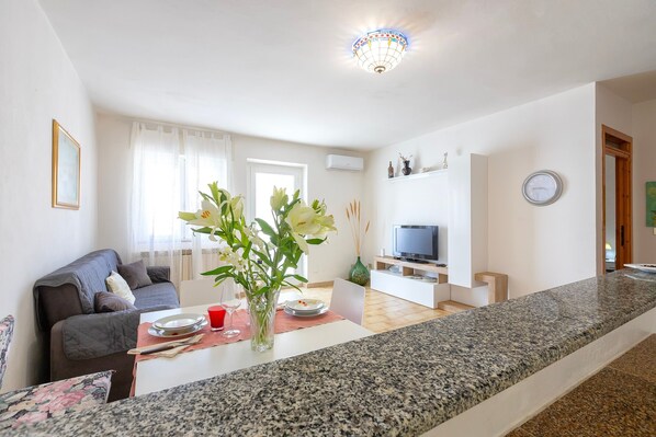 A modern living room with a sofa, dining table, and a TV.