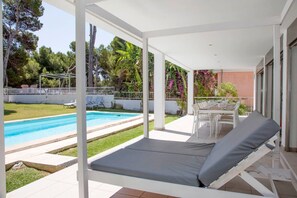 A covered outdoor area with a pool, lounge chairs, and a dining table. - Luxurious Holiday Home "Gemelos" with Sea View, Pool and Air Conditioning (Alcúdia)