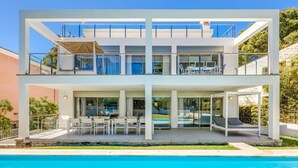 Una moderna casa a due piani con piscina, area salotto esterna e patio coperto.
