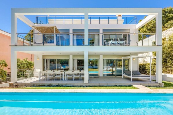 A modern two-story house with a swimming pool, outdoor seating, and a covered patio.