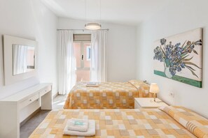 A hotel room with a bed, bedside table, lamp, and a painting of flowers on the wall. - Luxurious Holiday Home "Gemelos" with Sea View, Pool and Air Conditioning (Alcúdia)