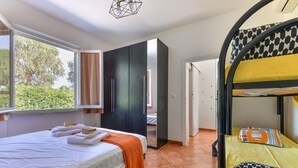 A bedroom with a bed, a wardrobe, a bunk bed, and a window. - Modern apartment with garden, air conditioning and Wi-Fi (LACONA - CAPOLIVERI (LIVORNO))