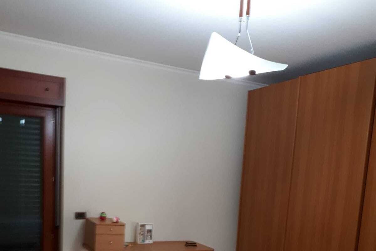 Une pièce avec une armoire en bois, un bureau avec une lampe et un tapis à rayures sur le sol.