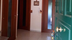 A hallway with a staircase leading to a room, a green door, and a ceiling light. - B&B Porta del Gargano (San Marco in Lamis)
