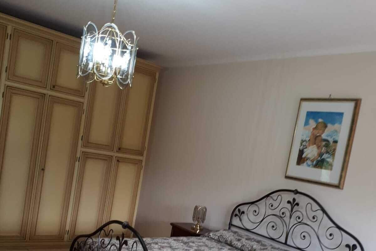 Une chambre à coucher avec un lit, un lustre, une armoire et un tableau encadré au mur.