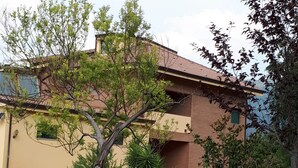 A two-story building with a flat roof, surrounded by greenery and a well-maintained lawn. - B&B Porta del Gargano (San Marco in Lamis)