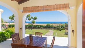 Une terrasse extérieure avec une table et des chaises en bois, une vue sur la mer et un espace jardin.