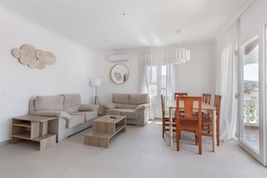 A modern living room with a sofa, coffee table, and dining table.