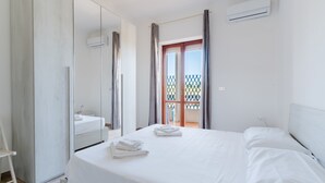 Habitación de hotel con cama, espejo, equipo de aire acondicionado y vista al exterior.