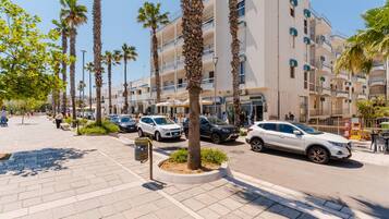A hotel with multiple floors, palm trees, and parked cars on the street.