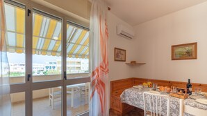 Une pièce comprenant un lit, une table à manger et offrant une vue sur l’extérieur grâce à une grande fenêtre.