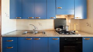 Une cuisine avec des armoires bleues, un évier en acier inoxydable, une cuisinière et un lave-vaisselle.