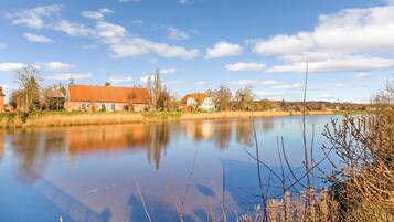 Ein ruhiger Fluss mit Häusern am Ufer, klarer Himmel und Bäume.