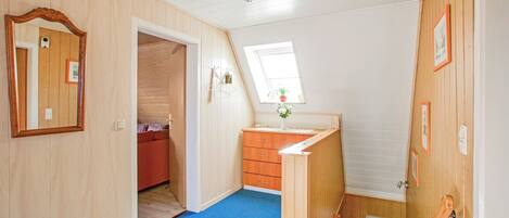 Ein Zimmer mit Holzwänden, blauem Teppich, einer Holztreppe und einem Fenster mit Pflanze.
