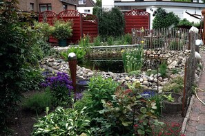 Un jardín con diversas plantas y un pequeño estanque.