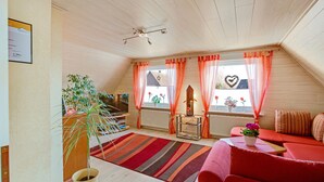 Een gezellige woonkamer met een rode bank, een gestreept vloerkleed en een plant in een pot.