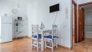 A small kitchen with a white refrigerator, microwave, and a dining table with two chairs.