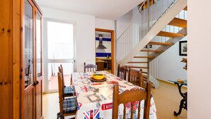A dining area with a table set for four, a staircase, and a view of the outdoors.
