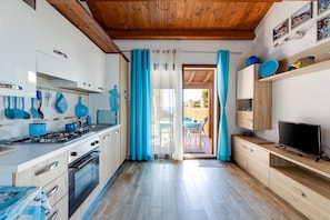 Una cocina moderna con armarios de madera, estufa a gas, horno y comedor con mesa y sillas.