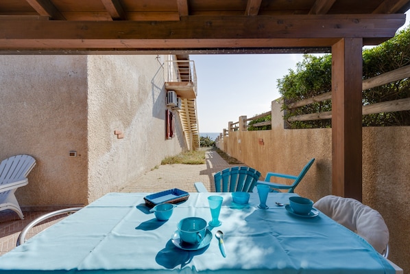 Un área de comedor al aire libre con una mesa para dos, sillas y vistas a una escalera que sube a un nivel superior.
