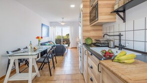 A modern kitchen with a glass dining table, a wooden countertop, and a view to the living area. - Modern and only a few steps from the sea - Apartamento Soñac S (Los caños de meca ( Cadiz))