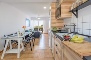 Une cuisine moderne avec une table à manger en verre, un plan de travail en bois et une vue sur l’espace de vie.