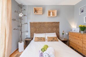 Une chambre d’hôtel bien rangée, avec un lit, une table de chevet, une commode et une plante fixée au mur.
