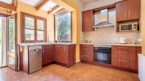 Eine Küche mit Holzschränken, einem Geschirrspüler, einem Backofen und einer Mikrowelle.