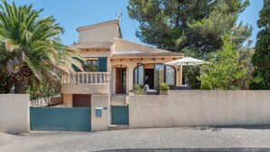 Ein zweistöckiges Haus mit Balkon, überdachter Terrasse und einem begrenzten Eingang.