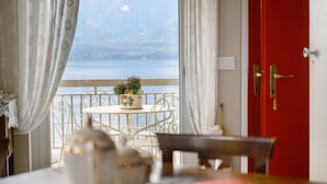 A room with a table set for tea, a view of the sea, and a red door.